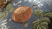 mosaic close up of a large restaurant sign showing a hazelnut, leaves and name