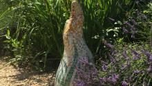 mosaic garden sculpture, organic in shape surrounded by summer flowers and lavender